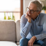 Worried senior man sitting alone in his home