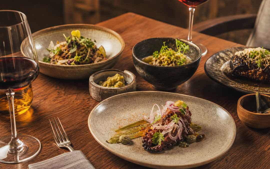 Platillos mexicanos contemporáneos y copas de vino en una mesa de experiencia gastronómica.
