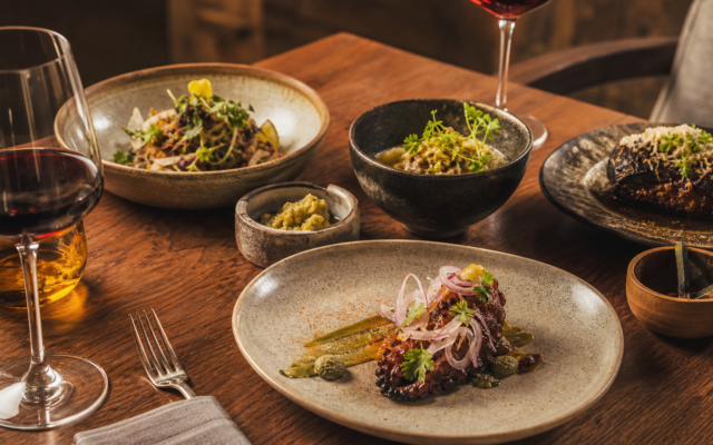 Platillos mexicanos contemporáneos y copas de vino en una mesa de experiencia gastronómica.