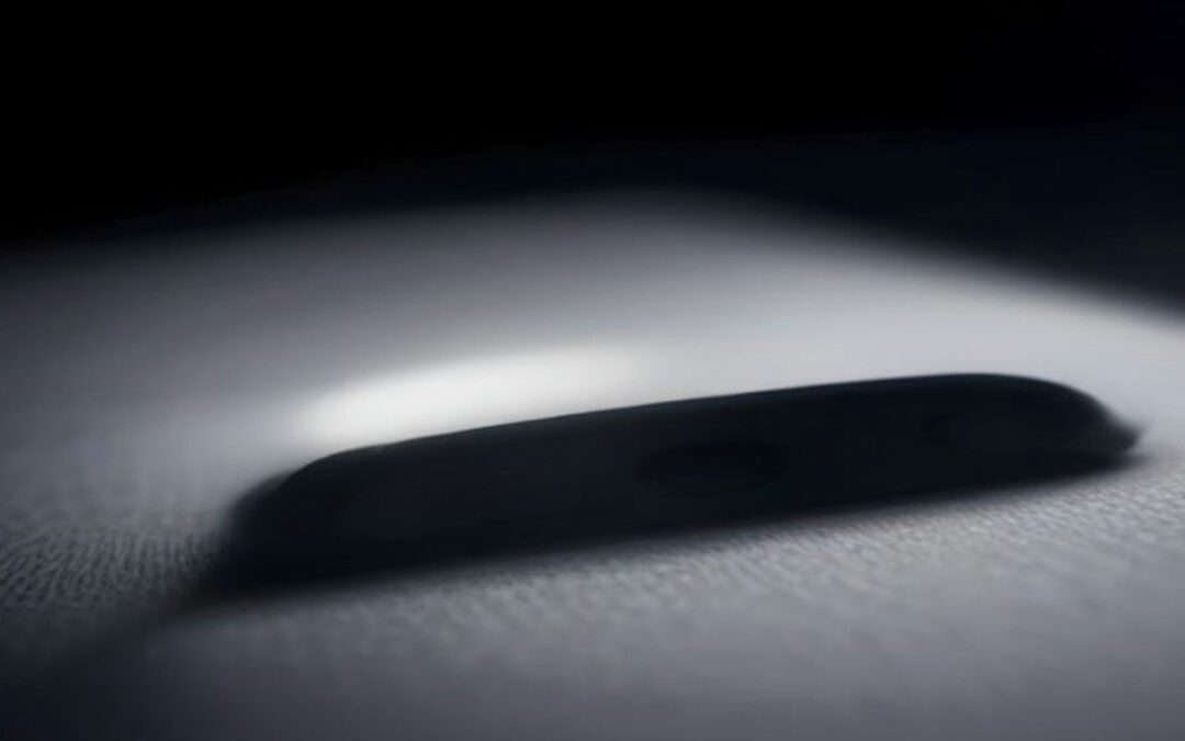 Silueta desenfocada de un teléfono celular sobre una superficie clara en penumbra, iluminada por un haz de luz lateral