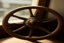Timón de madera de un barco junto a una ventana con luz tenue