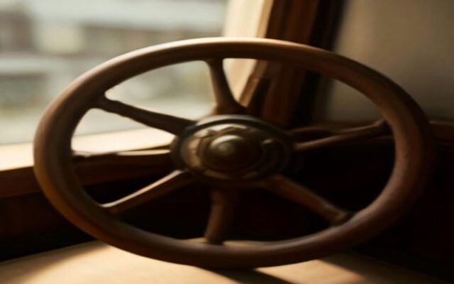 Timón de madera de un barco junto a una ventana con luz tenue